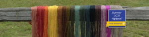 multi colored dyed wool drying on wooden fence